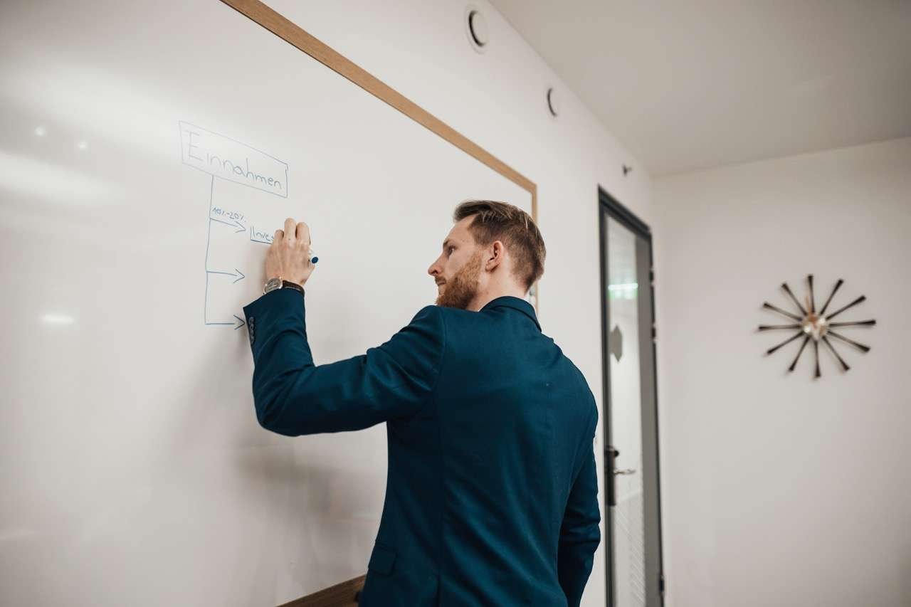 Lukas Rother, Geschäftsführer von MoneyMentor, erstellt Ideen auf einem Whiteboard.